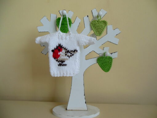Hand knit minature jumper ornament in white with an embroidered Christmas robin redbreast hanging on a wooden tree photo prop.